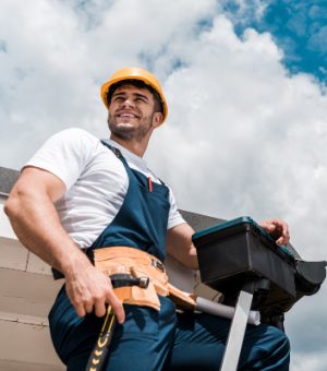 low angle view of happy repairman in helmet holding hammer and toolbox